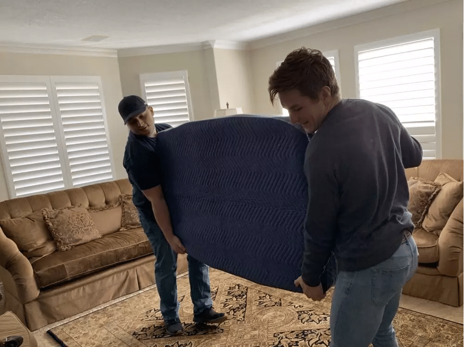 Best of Utah Moving Company movers carry padded furniture in a Sandy, Utah living room