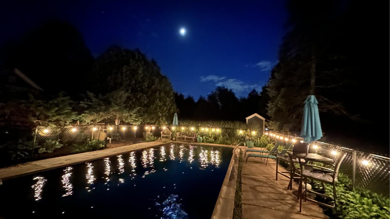 Backyard pool area with outdoor string lighting at night