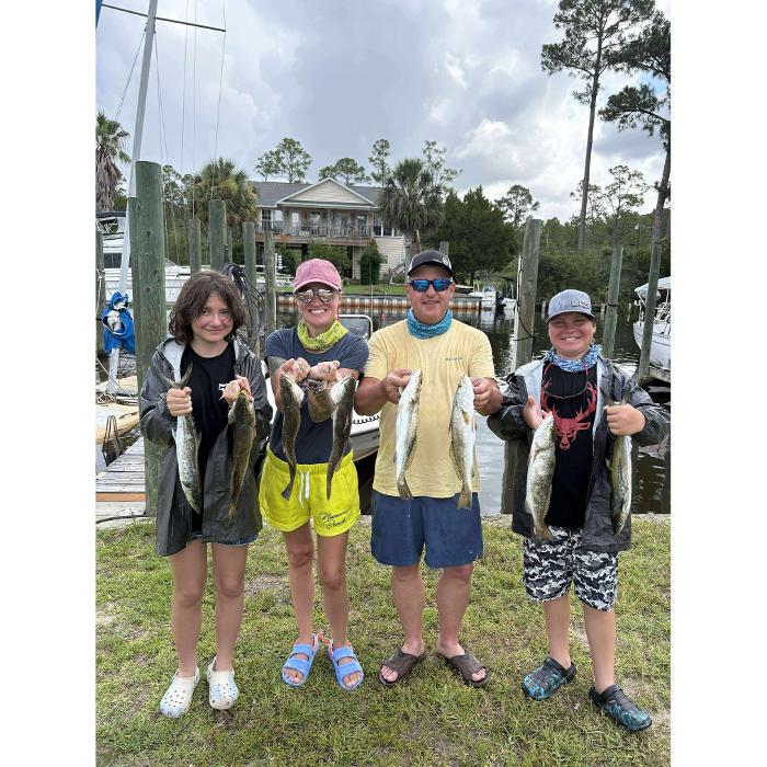 Family showing their catch after a Navarre fishing charter with Showintail Inshore Charters