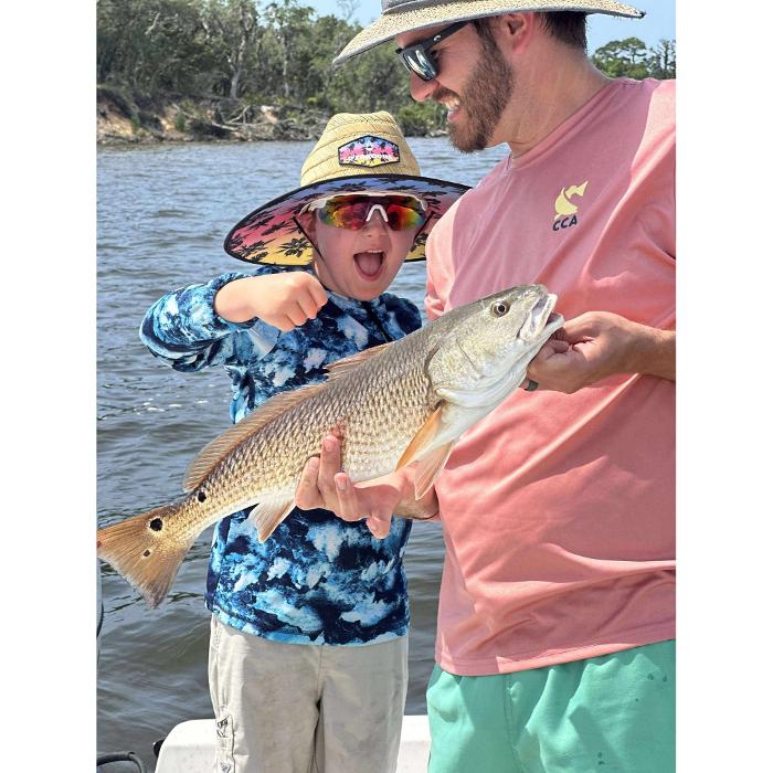 Excited young angler holding a redfish on a Showintail Inshore Charters trip in Navarre, Florida