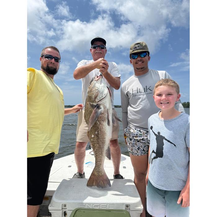 Group posing with a big black drum on a Navarre fishing charter with Showintail Inshore Charters