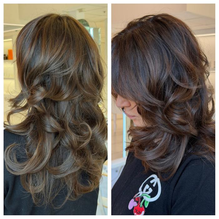 Layered brunette haircut with soft curls, face-framing bangs, and dimensional highlights at Logunova Beauty Salon
