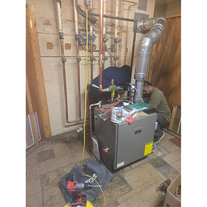 HVAC technicians installing a Lennox heating and air unit in a Washington, DC utility room.