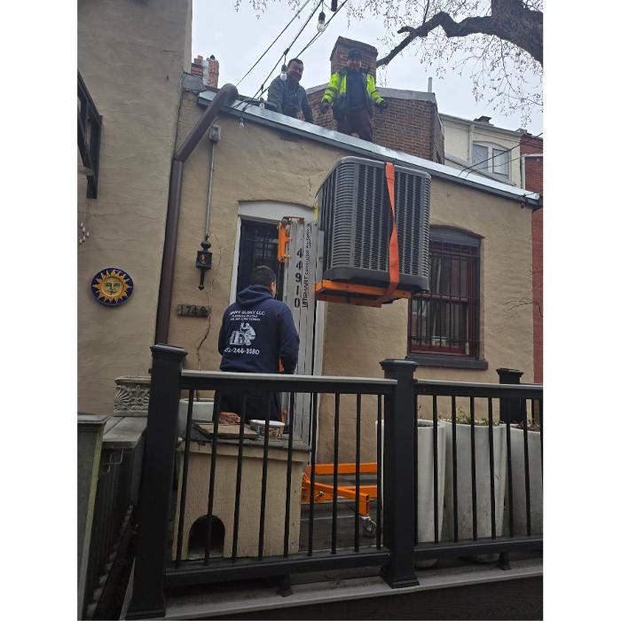 Jimmy Gusky technicians lifting an outdoor AC unit to a rooftop in Washington, DC.