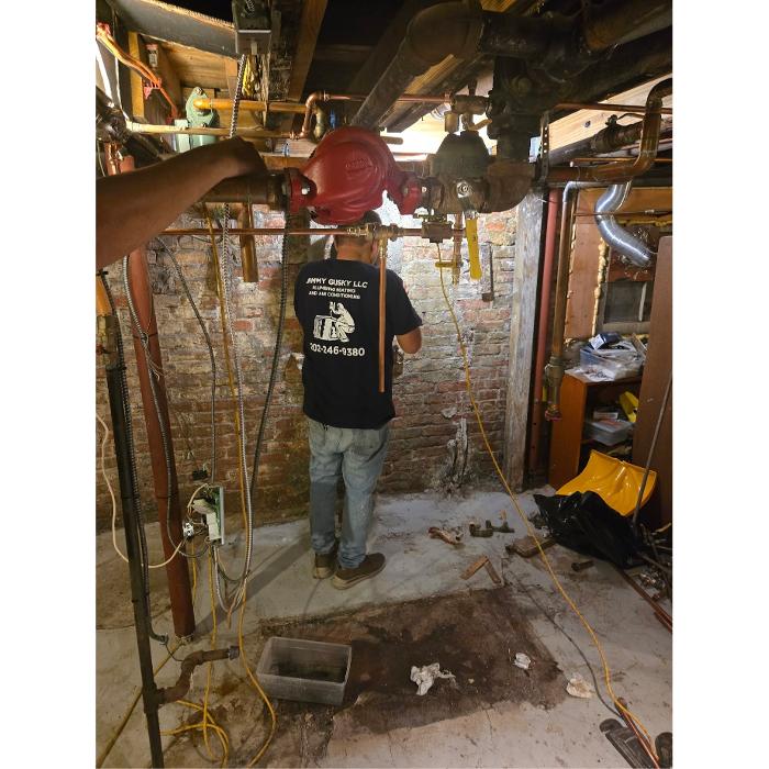 Jimmy Gusky HVAC technician working on basement piping and heating equipment in Washington, DC.