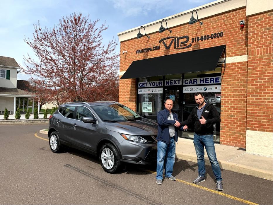 Customer receiving keys for a gray SUV outside VIP Auto PA in Feasterville-Trevose, Pennsylvania.