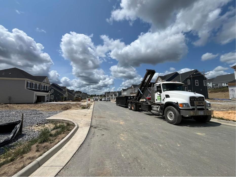 EZ Dumpster Services truck delivering a roll-off dumpster in a Staunton, Virginia neighborhood.