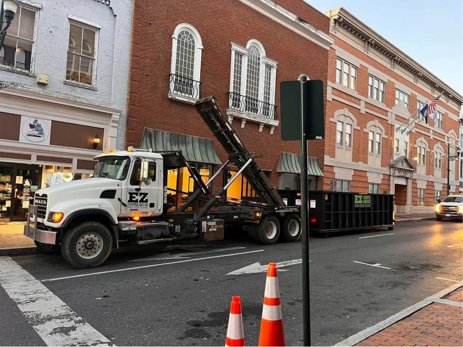 EZ Dumpster Services truck delivering a dumpster on a downtown street in Staunton, Virginia.