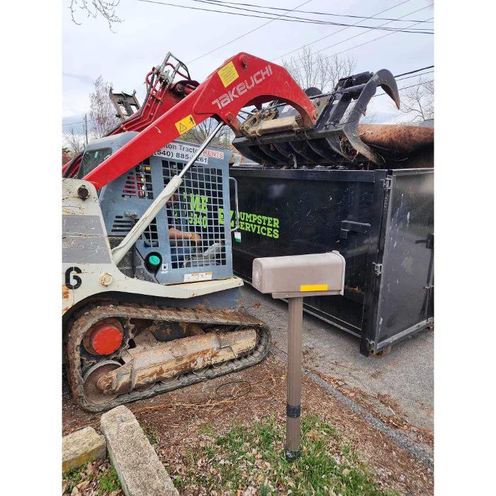 Skid steer loading debris into an EZ Dumpster Services rental dumpster in Staunton, Virginia.