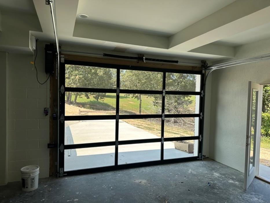 Black aluminum full-view glass garage door with floor-to-ceiling panels on a modern home — Hawk Garage Doors
