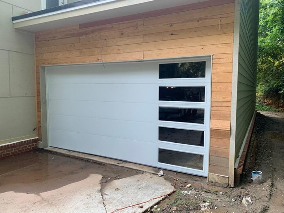 Modern white sectional garage door with horizontal glass panel inserts on a residential home — Hawk Garage Doors