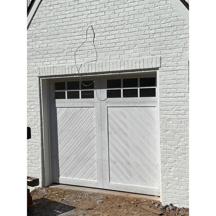 Classic white raised-panel garage door with decorative hardware on a residential home — Hawk Garage Doors