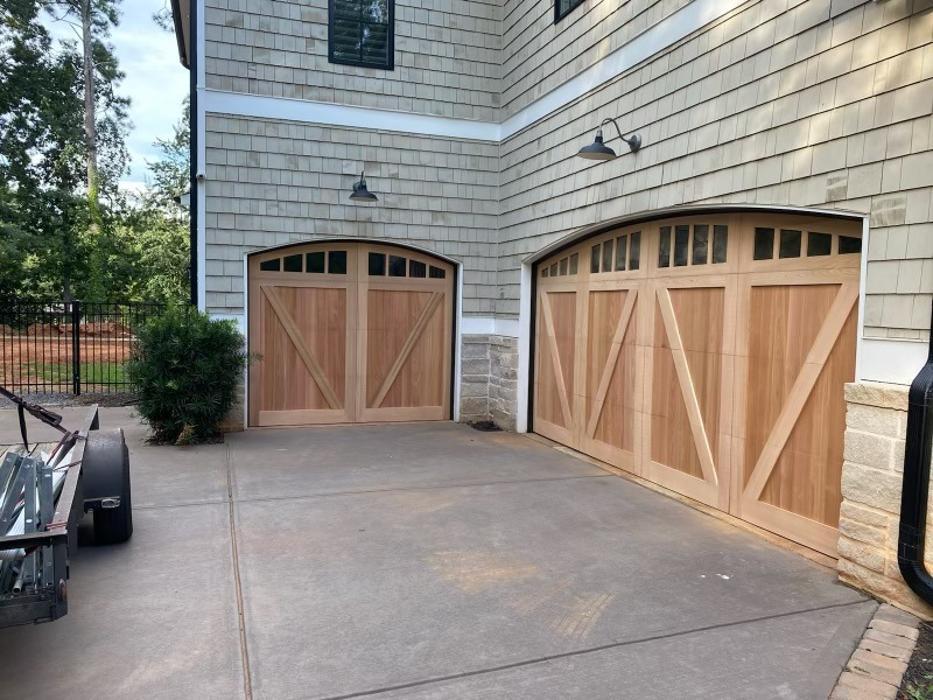 Traditional carriage-style wood garage door with arched window inserts and natural finish — Hawk Garage Doors