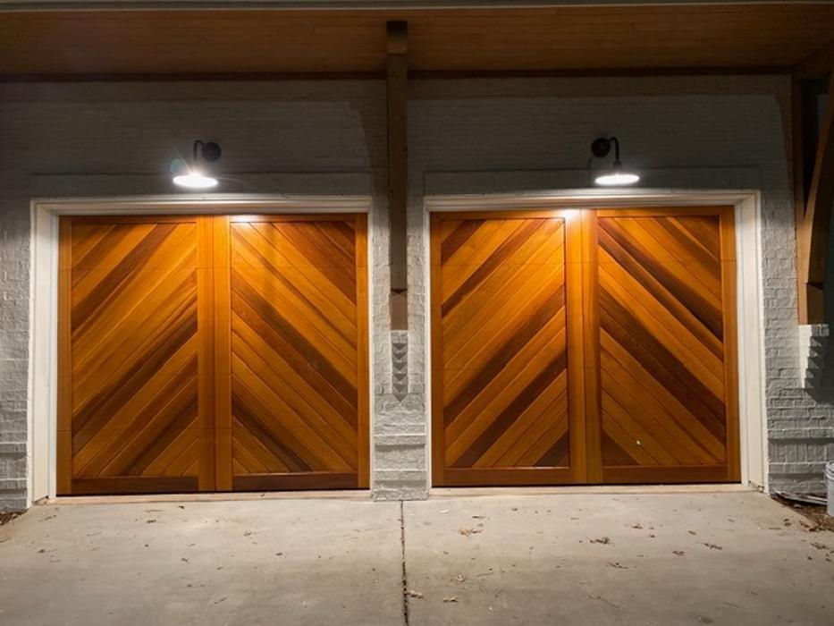 Warm wood double garage door illuminated at night, showing professional installation quality — Hawk Garage Doors