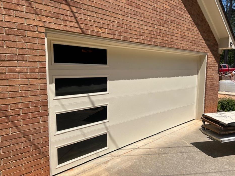 Full-view aluminum and glass garage door with horizontal dark frame panels installed on a brick home — Hawk Garage Doors