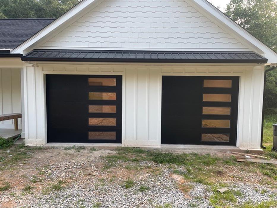 Contemporary white home with two-car garage featuring modern flush-panel doors and glass panel accent detail — Hawk Garage Doors