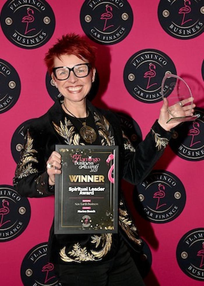 Marina Beech holding her Flamingo Business Awards winner certificate and glass trophy, Spiritual Leader Award, New Earth Business category