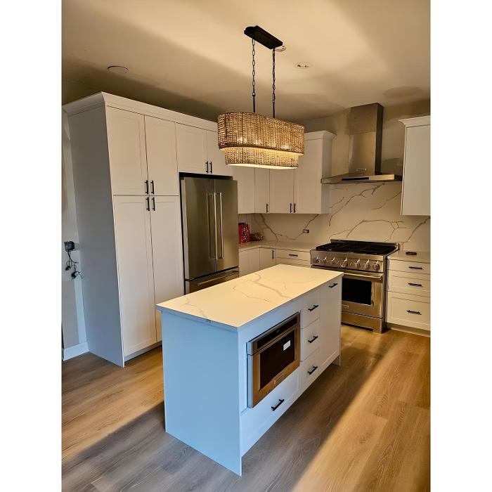 Finished kitchen remodel with white cabinets and island by Post Services Inc in Northfield, IL.