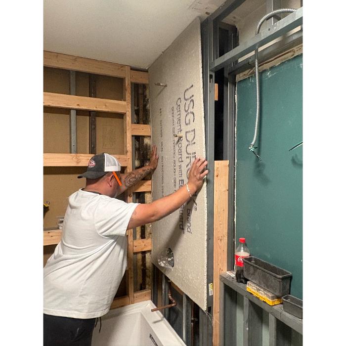 Contractor installing wall panels during a renovation by Post Services Inc in Northfield, IL.