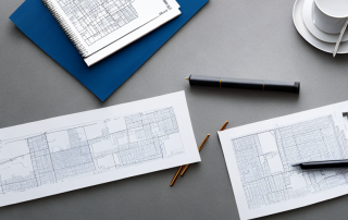 Gut organisierter Stadtentwicklungsplan auf Tisch mit Architekturwerkzeugen wie Linealen und Stiften, darstellt den sorgfaeltigen Planungsprozess.