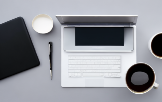 Pristiner Buero-Schreibtisch mit Laptop, Notizblock, Stift und Kaffee, symbolisiert Vorbereitung und Professionalitaet.