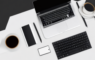 Schreibtisch Setup mit Laptop, Notizblock, Kaffeetasse und Stift in professioneller Umgebung.