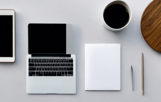 Moderner Arbeitsplatz mit Laptop, Kaffeetasse und Notizblock, ideal fuer das Erstellen von Bewerbungsunterlagen.