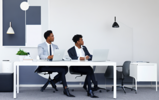 Selbstbewusste Person im Gespraech mit professionellem Coach in modernem Buero mit motivierender Dekoration und digitalen Geraeten.