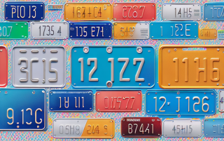 A variety of colorful vehicle license plates with a digital clock showing a short time
