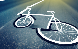 A bicycle lying on a road with a car's tire marks nearby
