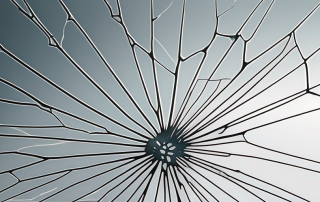 Nahaufnahme einer zersprungenen Windschutzscheibe mit Rissen durch Steinschlag, Schwerpunkt auf dem Schadensbereich.