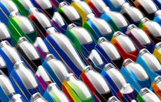 Various colored car polish bottles arranged in a row with a shiny car in the background