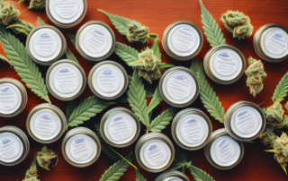 Several neatly arranged jars of cannabis salves with different colored lids