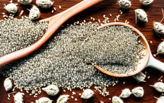 Unshelled hemp seeds scattered around a wooden spoon