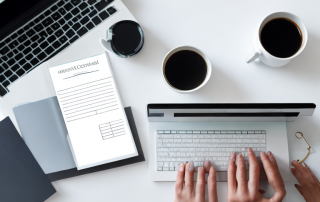 Ordentlich organisierter Schreibtisch mit Laptop, Vergleichstabelle, Kaffeetasse und Smartphone fuer Versicherungsvergleiche.