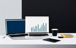Sauberer Arbeitsplatz mit Laptop, Kaffeetasse und Notizbuch zur effektiven Vergleichsanalyse von Versicherungsoptionen mit Diagramm auf dem Bildschirm.